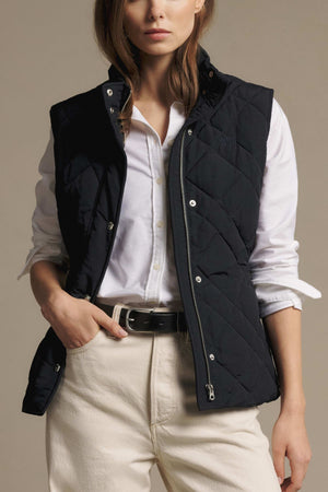 A person wearing a slim fit RM Williams Ikara Vest over a white button-down shirt and light-colored jeans.