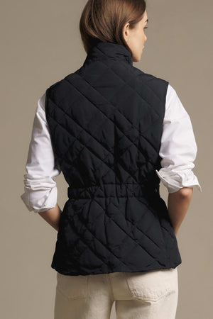 Back view of a person wearing a black, slim fit RM Williams Ikara Vest over a white long-sleeved shirt.