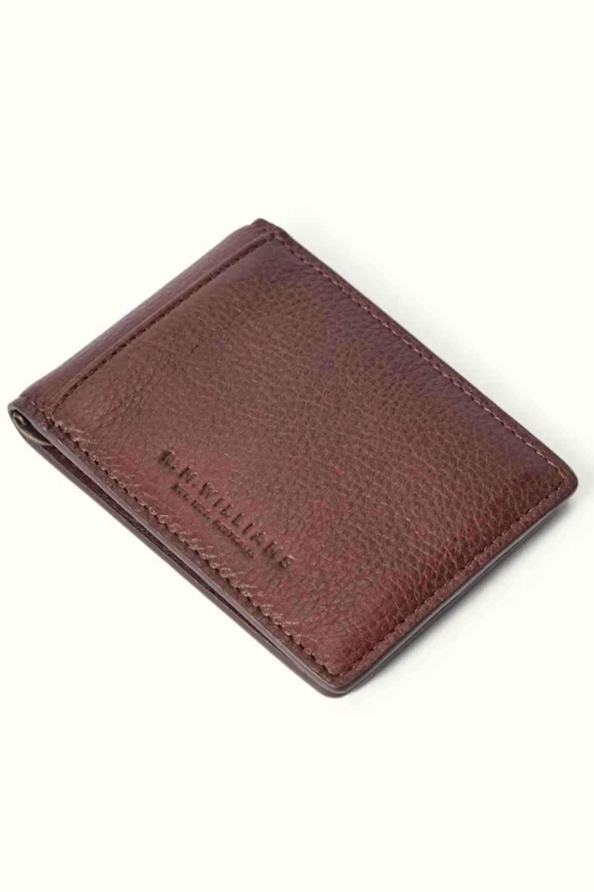 The RM Williams Farrier Bi Fold Wallet, crafted from brown premium leather with visible stitching and embossed with "R.M. WILLIAMS" on the front, features a modern closed design that stands out against a plain white backdrop.