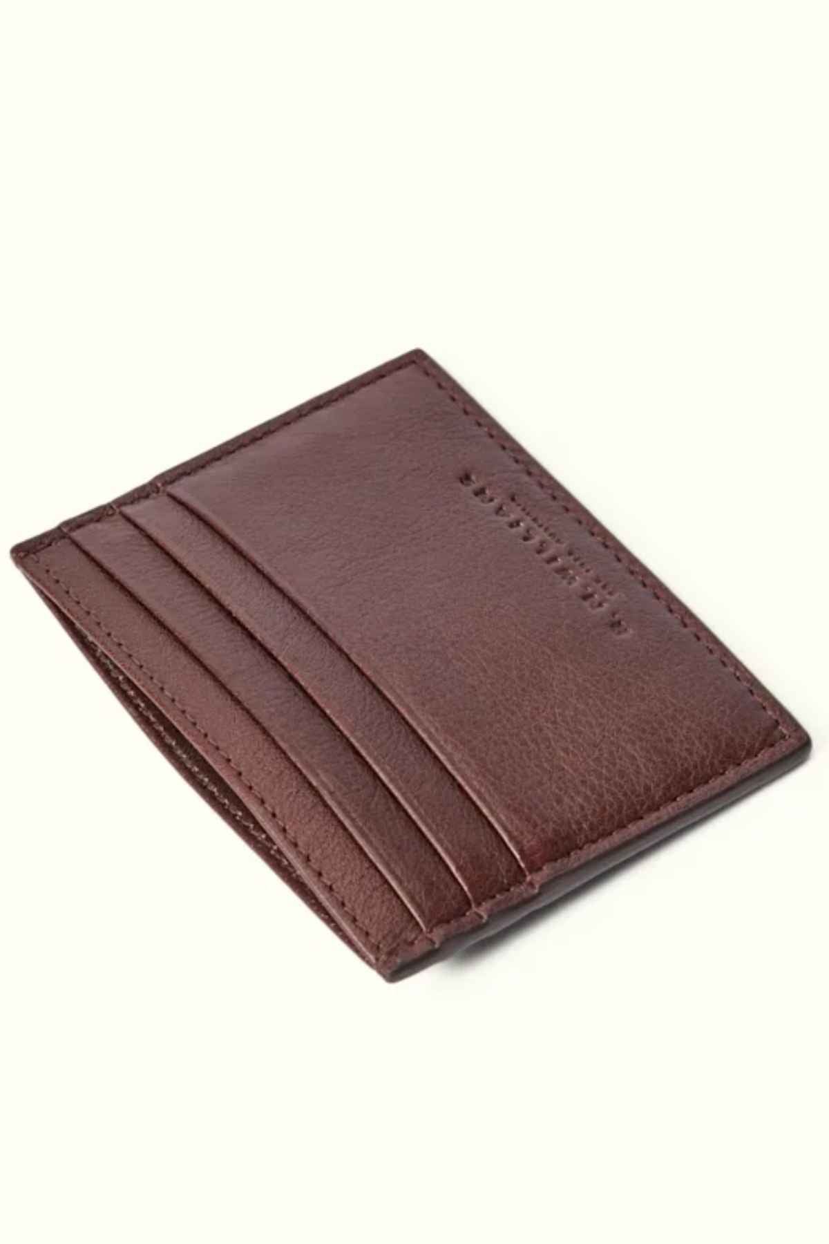 This RM Williams Farrier Card Holder, made from premium brown leather, features a simple and sleek design with four visible card slots. The prominent stitching along the edges adds to its elegance as it sits at an angle on a light background.