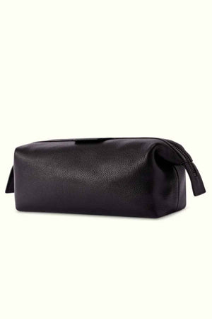A close-up of the RM Williams Farrier Washbag, featuring a black leather finish with a frog-mouth zipper. The rectangular-shaped bag showcases slight texture on the leather, set against a plain cream background.