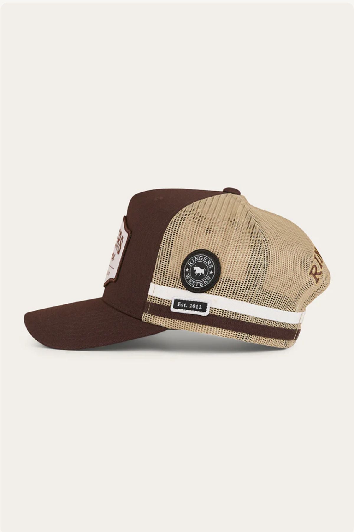 The Ringers Western Country Club Deep Fit Trucker Cap features a brown front and bill, beige mesh back, and embroidered patches. The side patch displays a circular logo and "Est. 2012" for classic country style.