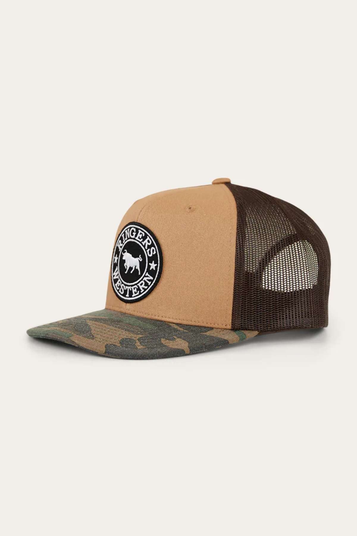 The Ringers Western Dalby Trucker Cap features a tan and camouflage design with a black and white circular horse patch. Made from cotton twill, it has a mesh back and an adjustable snapback closure for the perfect fit.