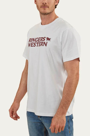 A man wears a Ringers Western Hastings Loose Fit T-Shirt crafted from 100% cotton jersey, marked with "Ringers Western" in maroon and a small horse logo. He pairs it with blue jeans against a plain, light-colored backdrop.