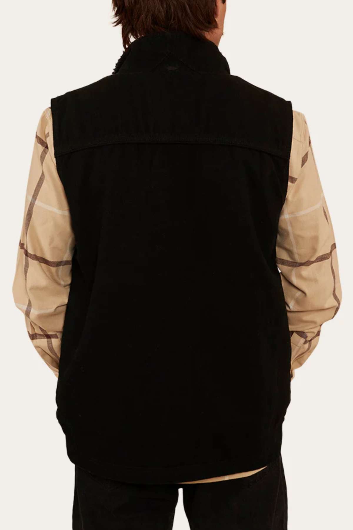 Revised: A rear view showcases a person wearing the Ringers Western High Country Vest over a beige plaid shirt. With brown hair and their back to the camera, the individual stands against a neutral, light-colored background, evoking an outdoor adventure setting.