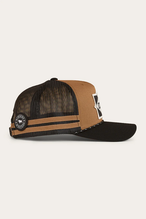 The Ringers Western Hometown Trucker Cap features a brown and black deep fit design, mesh back, adjustable snapback, two horizontal stripes, and front patch. A circular logo patch accents the side near the back.