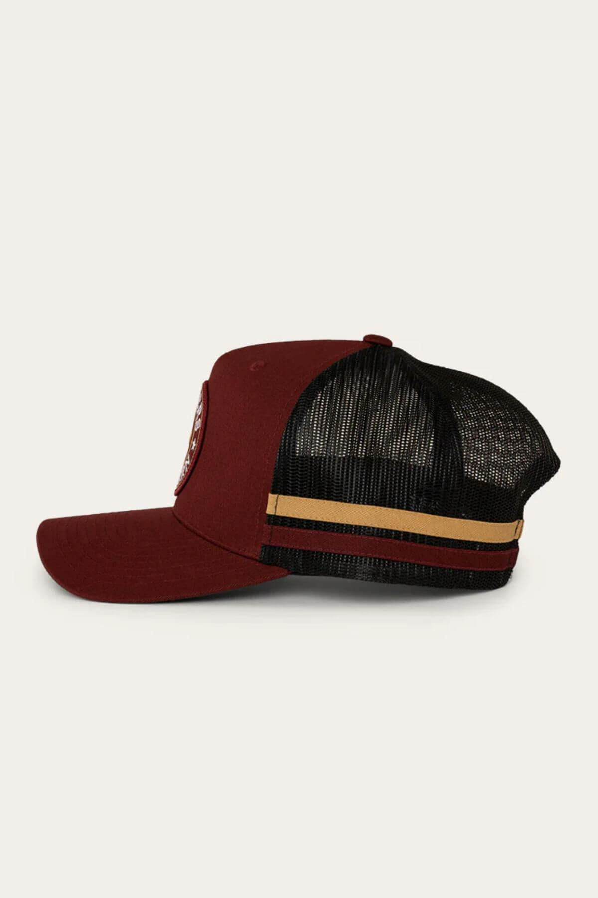 Side view of the Ringers Western McCoy Trucker Cap featuring a solid maroon cotton twill front panel, maroon brim, front patch, and a black mesh back with two horizontal tan and gold stripes.