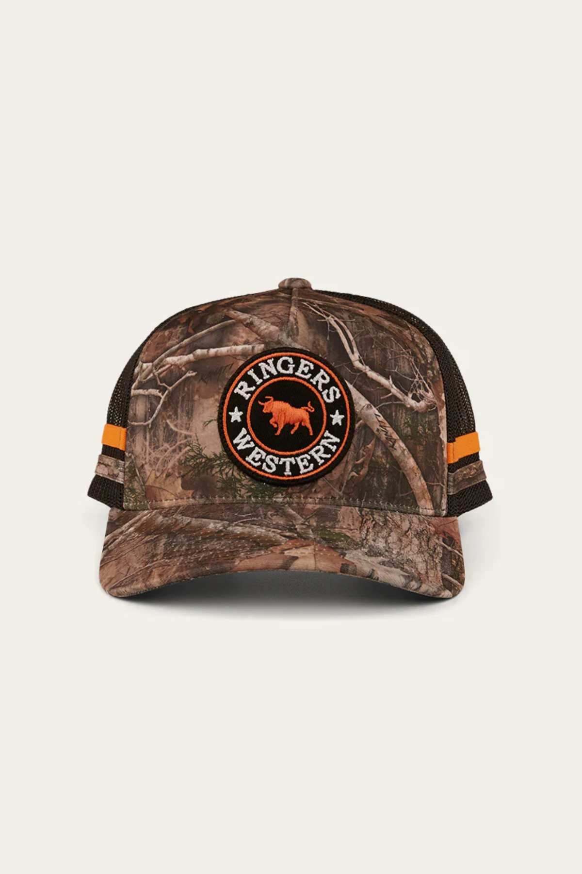 The Ringers Western McCoy Trucker Cap is a cotton twill camouflage design featuring "Ringers Western" text and animal logo on the front, with a breathable mesh back, vibrant orange side stripes, and a plain backdrop enhancing its rugged style.