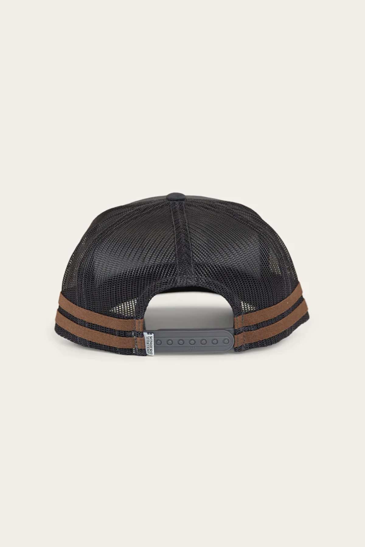 The Ringers Western McCoy Trucker Cap is black with a mesh back, featuring a snapback closure and two brown horizontal stripes on the brim, shown from the back.