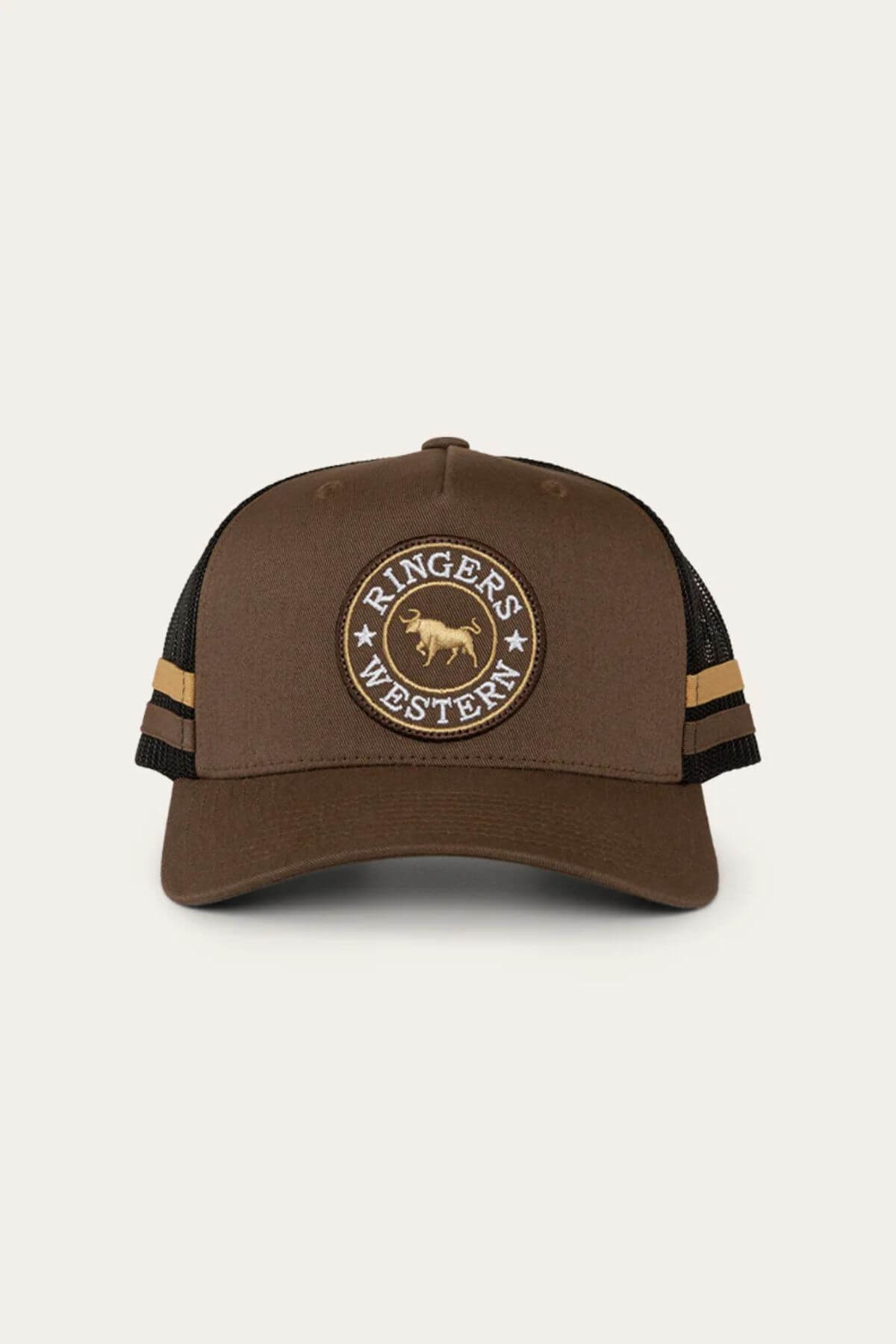 The Ringers Western McCoy Trucker Cap features a brown cotton twill front with a circular patch showing a bull silhouette and "Ringers Western" text, complemented by a black mesh back and two horizontal brown stripes on the sides.