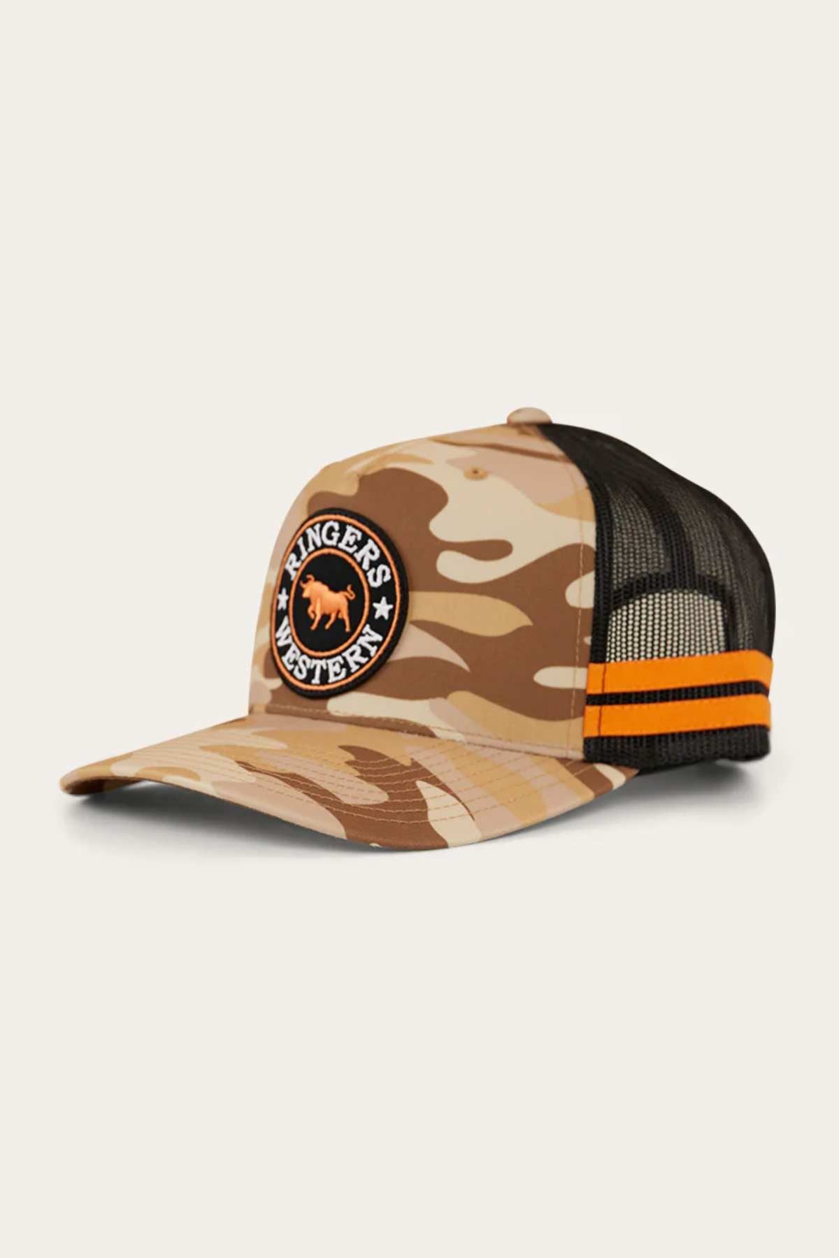 The Ringers Western McCoy Trucker Cap is beige and brown with a black mesh back, an orange and black bull logo patch reading "Ringers Western" on the front, and two bold orange stripes on the brim’s side.