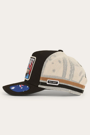 The Ringers Western Mud Sweat Beers Deep Fit Trucker Cap is black and beige with a front patch, flag design under the bill, “Est. 2012” side label, and features an adjustable snapback closure for a perfect fit.