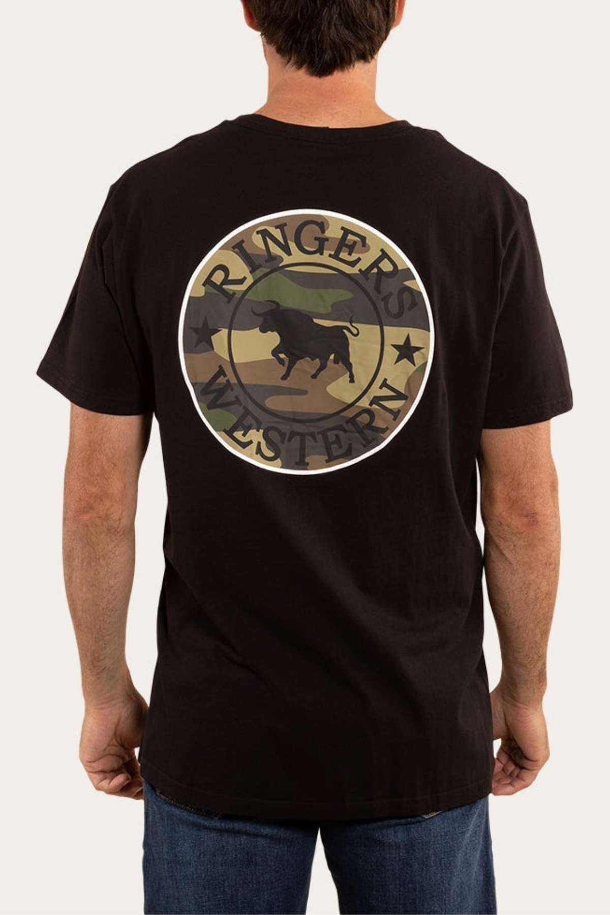 A person is seen from the back wearing the Ringers Western Signature Bull Classic T-Shirt, a comfortable black tee with a camouflage-patterned circular logo featuring a bull. The logo includes the text "Ringers Western." Paired with blue jeans, this casual look defines effortless style.
