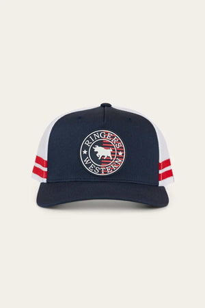 The Ringers Western Signature Bull Flag Trucker Cap features a navy blue and white design with red side stripes, a circular bull logo patch on the front, and an adjustable snapback closure for comfort.