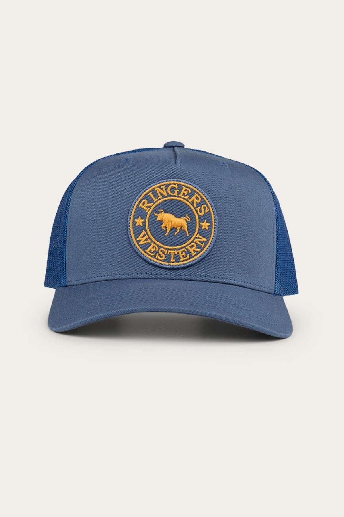 The Ringers Western Signature Bull Trucker Cap is a blue hat with a round yellow embroidered patch that says "Ringers Western" and features a bull emblem in the center. It has a mesh back and an adjustable snapback closure.