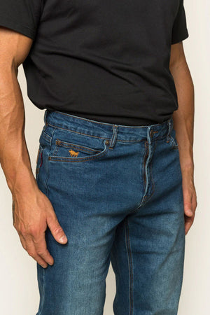 A person wears a black T-shirt with Ringers Western Sturt Men's Relaxed Leg Jeans, thumb hooked in the pocket. The jeans have a small brown label on one pocket, with only the torso and legs visible.