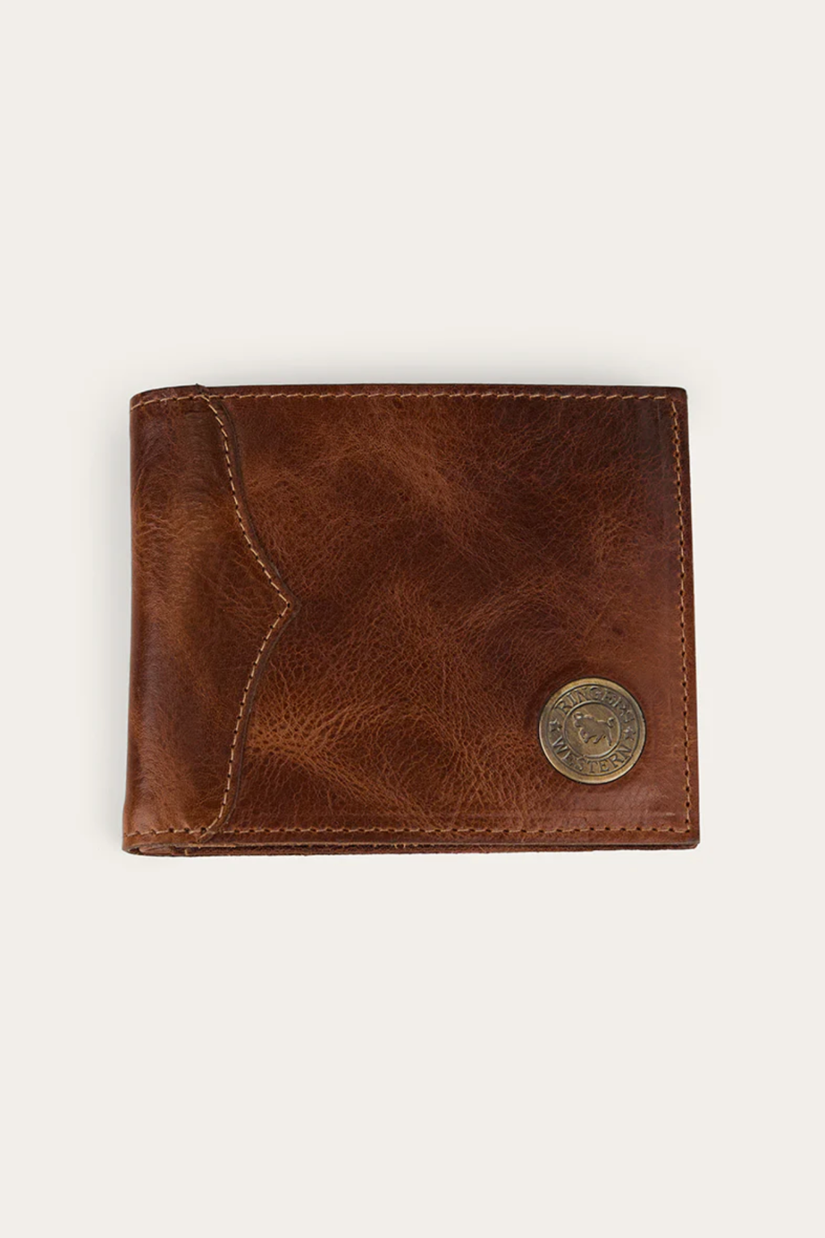 The Ringers Western Toro Midi Wallet is a slim, full-grain leather wallet featuring visible stitching and a round metallic emblem in the lower right corner, shown against a plain, light background.
