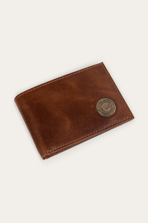 The Ringers Western Toro Slim Wallet, made from full grain leather, features a round brass emblem with an embossed animal design on the bottom right corner and is displayed on a light beige background.