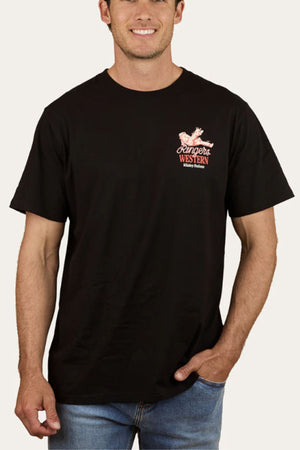 A man wears the Ringers Western Whiskey Business Loose Fit T-Shirt in black, featuring a small red and white logo on the left chest, paired with light blue jeans. He stands against a plain background, showcasing classic western style.