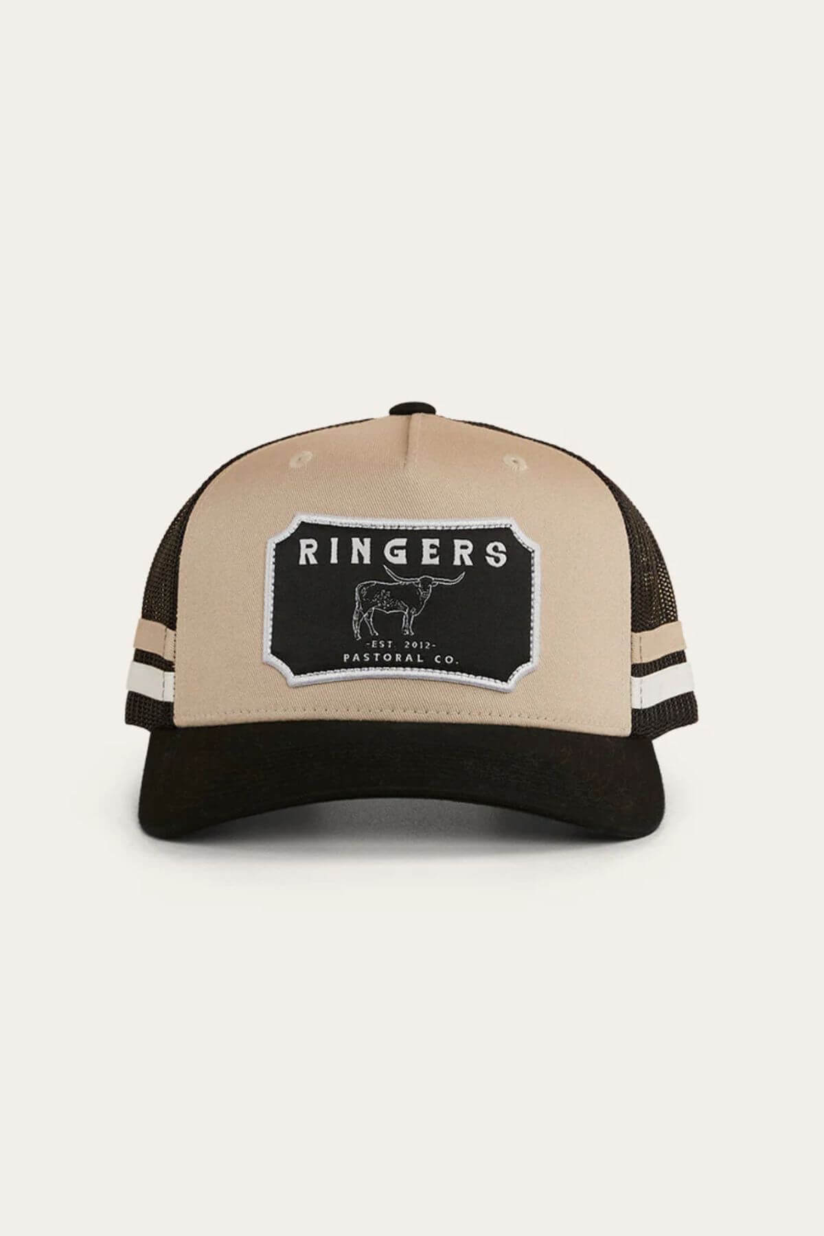 The Ringers Western Winston Trucker Cap is beige and black cotton twill with a black "RINGERS Pastoral Co." bull patch, two white side stripes, and a black mesh back.