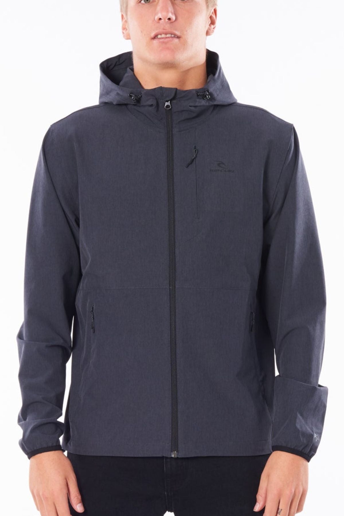 A person stands against a white background wearing the Rip Curl Anti Series Elite Jacket in dark gray with front pockets.