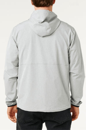 A person is seen from behind wearing the Rip Curl Anti Series Elite Jacket in light gray with long sleeves, a relaxed fit, and dark pants. The background is plain and light-colored.
