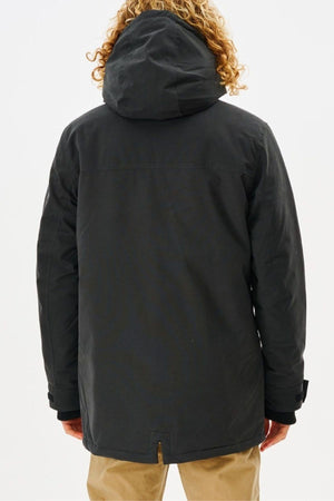 A person with curly hair, back to the camera, wears a Rip Curl Anti Series Exit Jacket and khaki winter clothes against a plain light background.