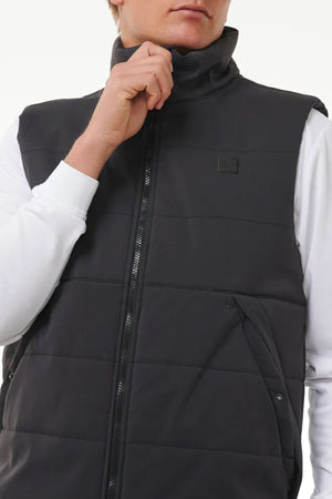 A person adjusts the collar of a Rip Curl Anti Series Ridge Vest, shown from shoulders to waist over a white long-sleeve shirt, highlighting the quilted padded lining.