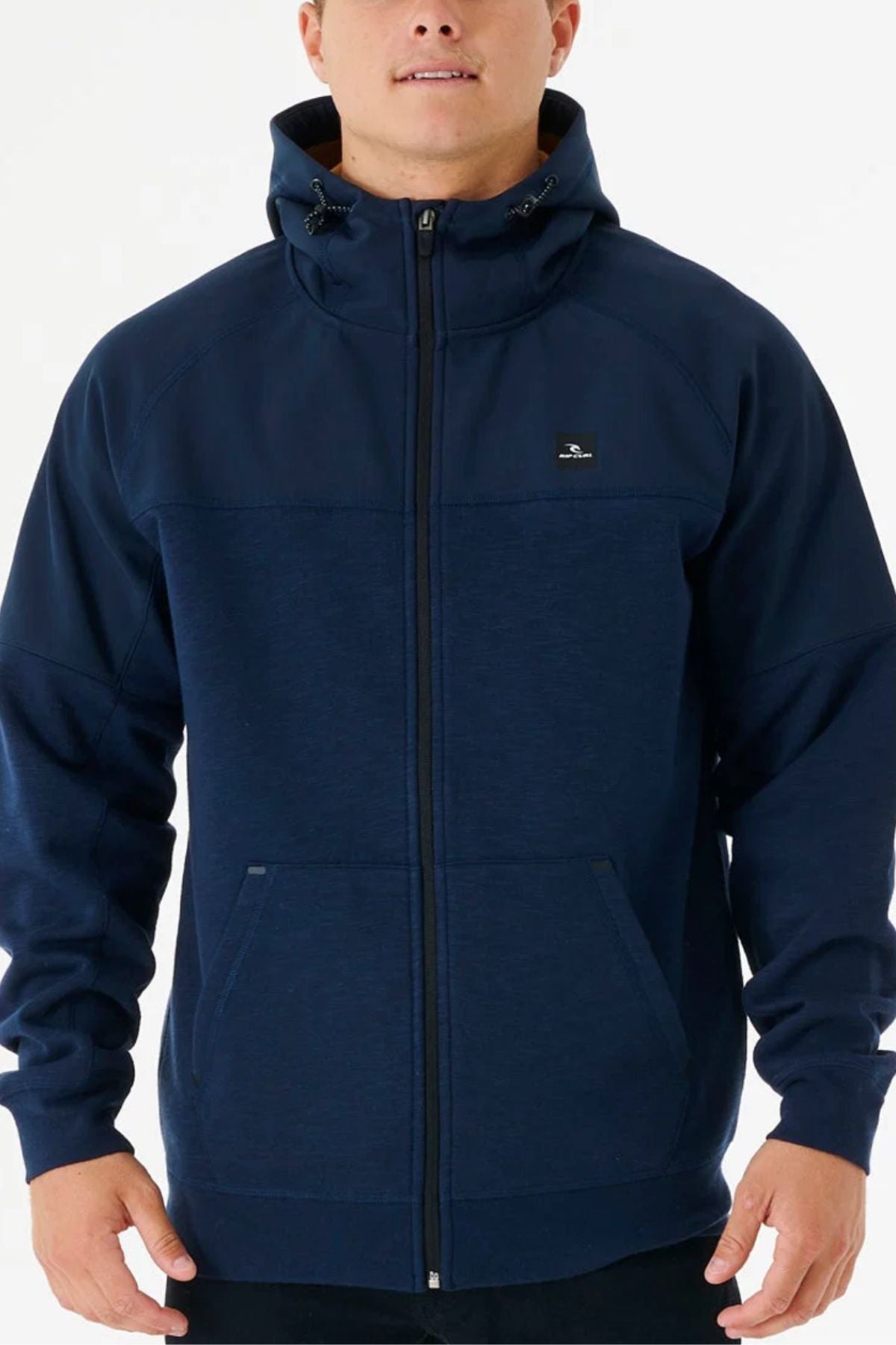 A person wearing the Rip Curl Anti Series Viral Zip Thru jacket in navy blue, featuring a hood, front pockets, and a small chest logo, stands against a plain white background. This jacket blends style with performance.