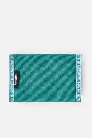 A Rip Curl Archive Cord Surf Wallet in green, featuring a decorative blue and white pattern along the edges. A black tag labeled "Rip Curl" is attached on the left side of the wallet, set against a plain white background.