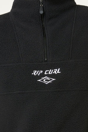Close-up of the Rip Curl Bells Polar Fleece, showcasing its soft black fleece, half-zip design, zip pockets, and a white embroidered "RIP CURL" logo with wave on the chest.