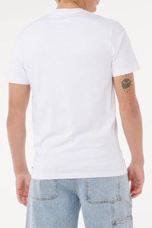 Person standing with their back to the camera, wearing a Rip Curl Big Mumma Icon Tee in plain white and light blue denim jeans. A tattoo of an eye with dripping details is visible on their upper right arm.