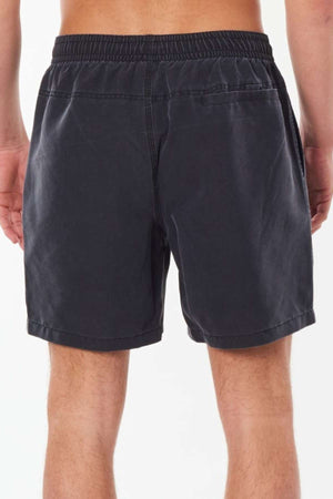 A person is shown from behind wearing the Rip Curl Bondi Volley shorts, which are dark, knee-length with an elastic waistband. These board shorts come with pockets and are made from casual, lightweight recycled PET fabric, set against a plain white background.