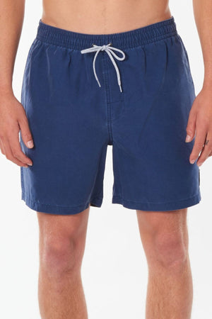 A person is wearing blue Rip Curl Bondi Volley swim trunks featuring a white drawstring, made from recycled Polyester Ripsuede. Positioned against a plain white background, the image centers on the shorts from waist to mid-thigh. The design includes quick-dry technology for enhanced comfort and practicality.