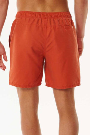Rear view of a person wearing orange Rip Curl Bondi Volley swim trunks, made from recycled PET, set against a white backdrop. The shorts include an elastic waistband and a small back pocket on the right side.