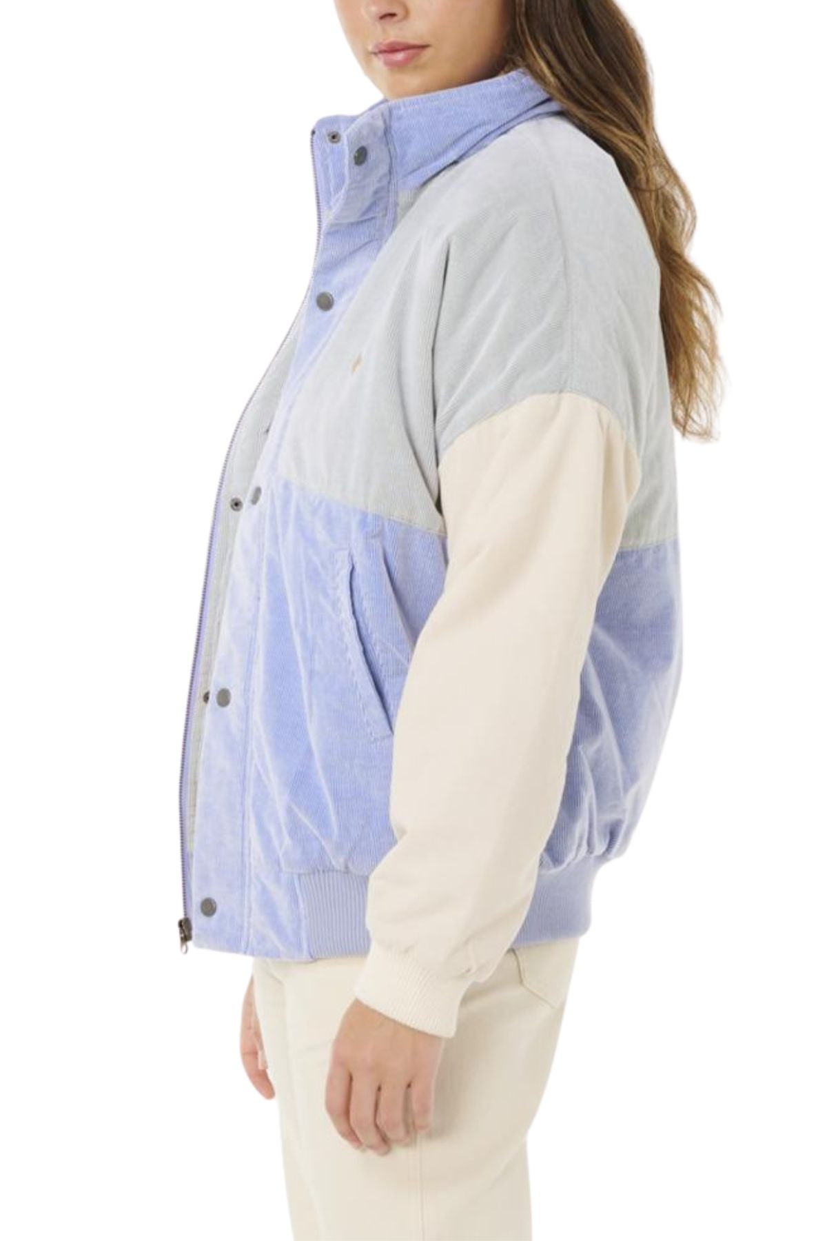 Someone in the Rip Curl Cala Vadella Jacket, featuring light blue and beige with cream sleeves, paired with matching light pants and facing sideways, showcases a cool retro style.