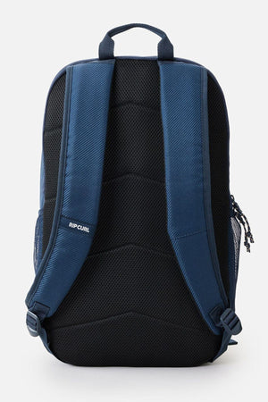 The Rip Curl Chaser 33L Backpack boasts a stylish navy blue and black design made from recycled polyester. It is equipped with padded shoulder straps and a top handle, making it ideal for daily use. The backpack also features a compartment that safely accommodates a 15" laptop, with the "RIP CURL" branding prominently displayed on the back panel.