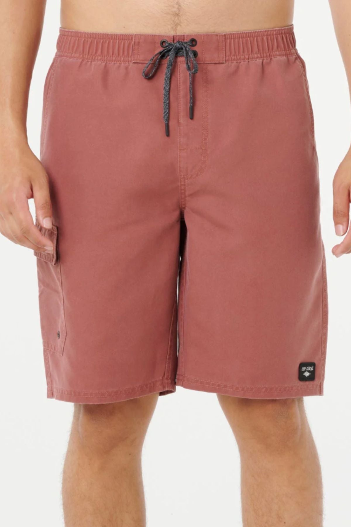 A person wearing Rip Curl Classic Surf Cargo Shorts in reddish-brown with a black drawstring, standing against a white background. Only the shorts and lower torso are visible.
