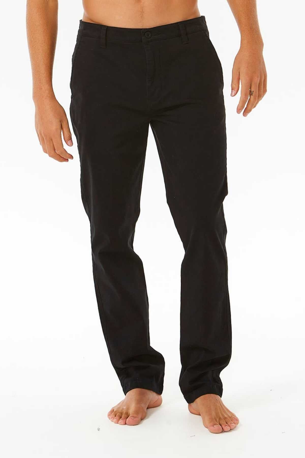 A person is barefoot against a white background, wearing black straight-leg Rip Curl Classic Surf Chino pants made from stretch cotton twill. These chinos offer a casual yet refined everyday style from waist to feet.