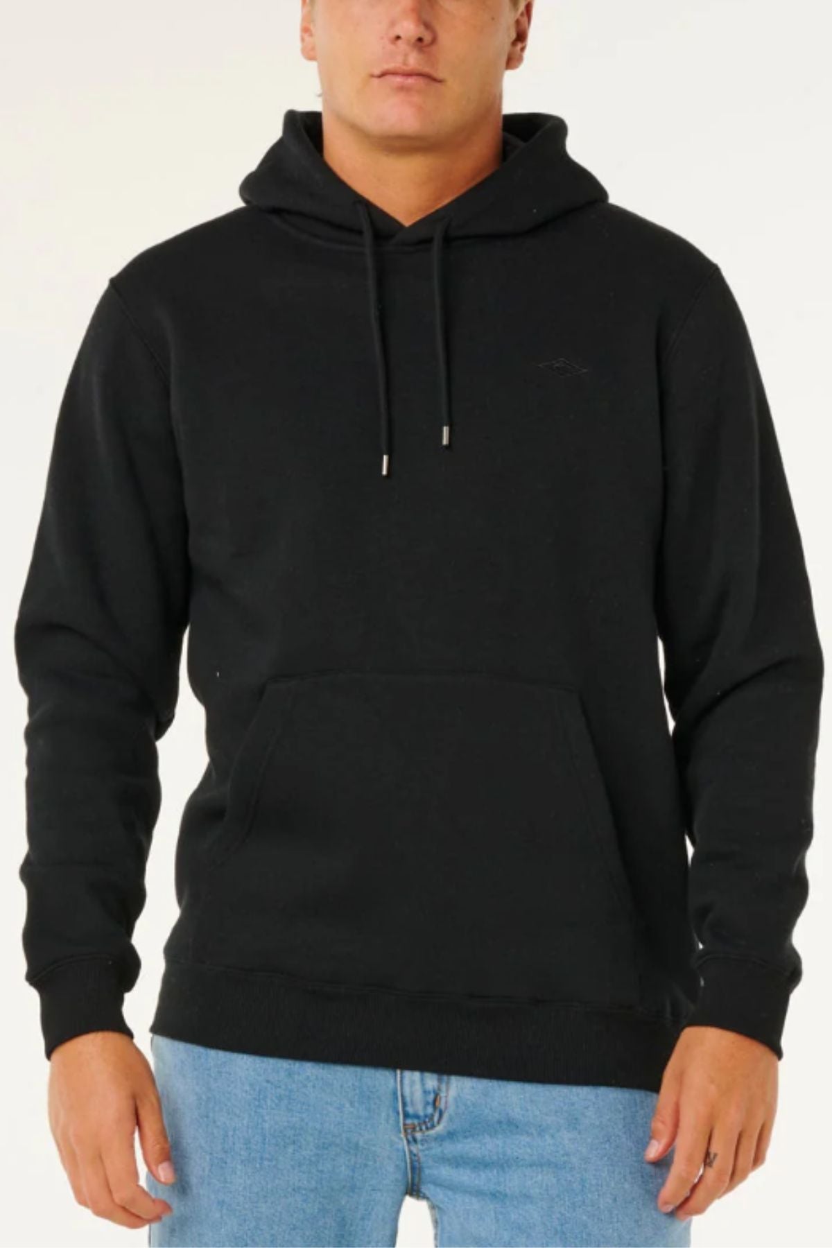 Someone wearing the Rip Curl Classic Surf Hood in plain black with a front pocket and light blue jeans stands against a white background.