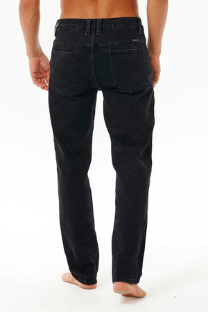 A barefoot person stands with their back to the camera, wearing Rip Curl Classic Surf Jean, against a plain white background.