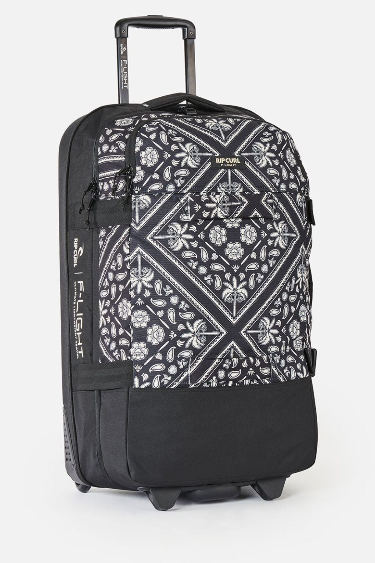 The Rip Curl F-Light Global 100L Bossa Nova is a check-in roller bag with a geometric and floral black-and-white design, extended handle, side pocket, AirTag sleeve, and Rip Curl branding on the top and side.