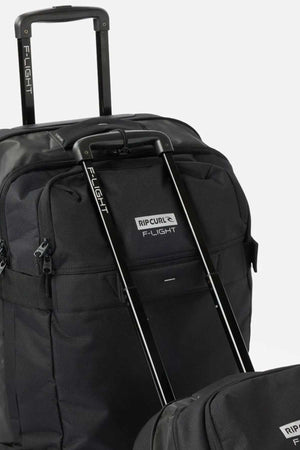 A close-up of two black Rip Curl F-Light Global 100L Icons rolling travel bags with extended handles. The bags prominently display the "F-Light" branding on the handles, and the front pocket of the larger bag features a visible Rip Curl logo. The background is plain white.