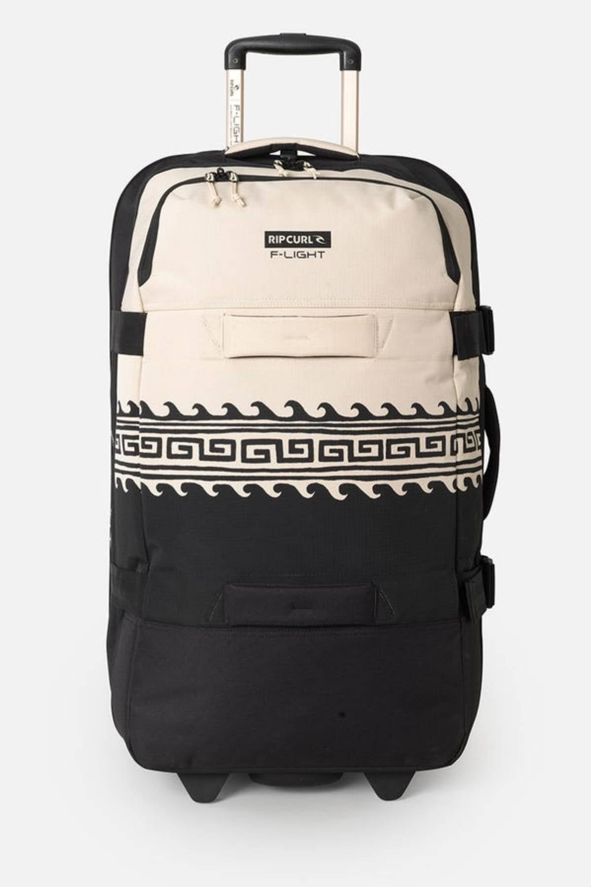 The Rip Curl F-Light Global 100L Soleil Travel Bag, made from recycled polyester, features a rolling suitcase design with a handle. The beige top displays the logo and dual zippers; the black bottom has a white wave pattern. It includes wheels, compression straps, and a front zippered pocket.