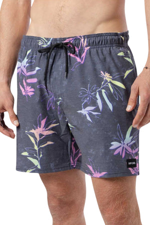 A person is wearing the Rip Curl Fun Times Volley, dark swim trunks adorned with a vibrant floral pattern and crafted from Rip Curl's quick-dry fabric. The shorts feature a drawstring waistband and display a small logo tag on the left leg. The upper body is bare, exposing part of the torso and hip.