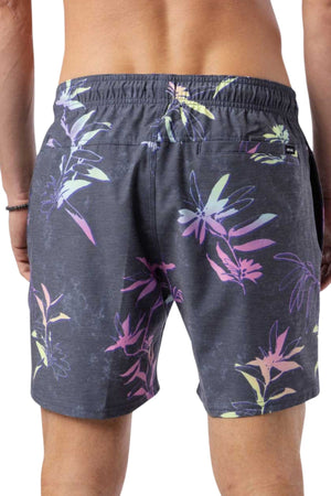 A person wearing Rip Curl Fun Times Volley swim trunks with a colorful floral pattern stands with their back to the camera. The shorts, featuring pink, purple, and yellow leaves, boast an elastic waistband and quick-dry fabric for added convenience.