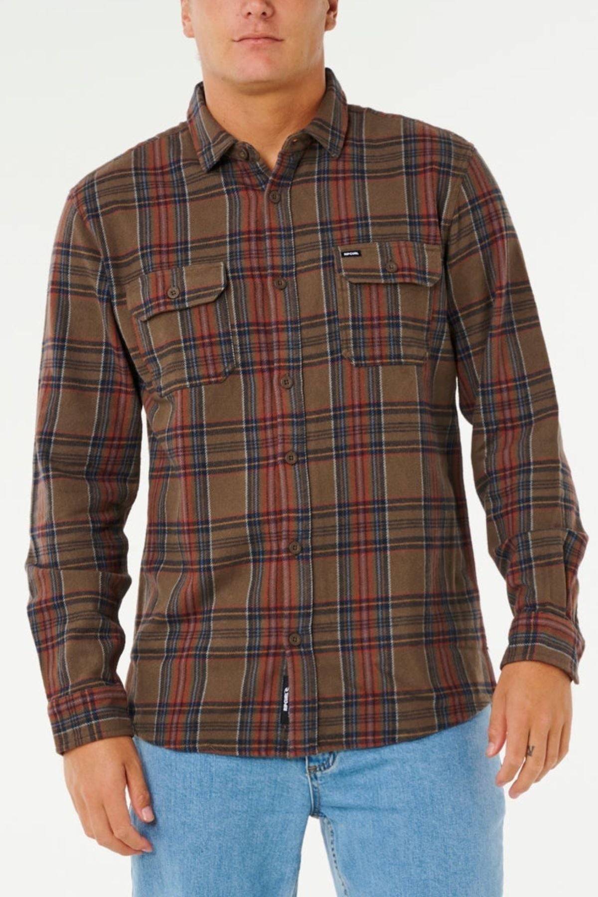 A person wears the Rip Curl Griffin Flannel Shirt in brown and red plaid with two chest pockets, paired with light blue jeans, standing against a plain white background.