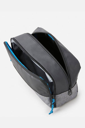 The Rip Curl Groom Toiletry Icons Of Surf bag features a gray and black design with blue accents, a zippered closure, spacious two-compartment interior for organizing personal items or electronics, and a stylish surf-inspired pattern—ideal for travel.