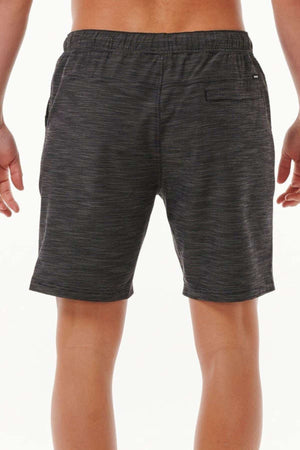 A person is wearing the Rip Curl Boardwalk Jackson Volley shorts in dark gray, featuring an elastic waist and a quick-dry fabric. The view is from the back, displaying the back pocket against a plain white background.