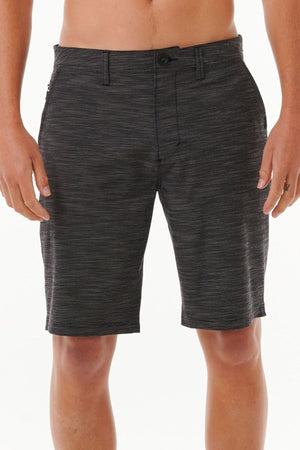 A person is wearing the Rip Curl Jackson Boardwalk shorts in dark gray, which are knee-length with a subtle striped pattern. These quick-dry shorts feature a button and zipper closure, making them perfect for any adventure. The background is plain white.